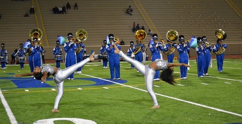 two acrobatic girls with marching band in background